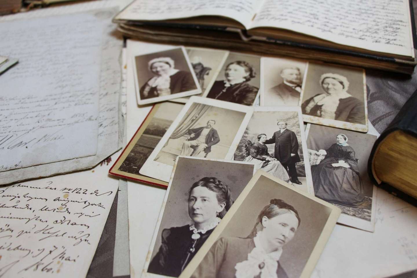 open handwritten diaries and rows of vintage potraits of men and ladies