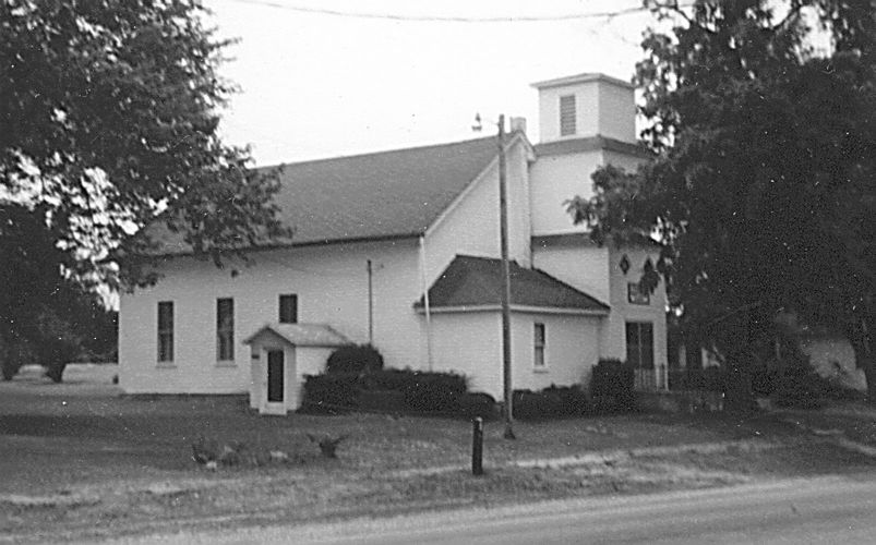 black and white photograph of rural church external sideview of entrance, belfry, side of sanctuary
